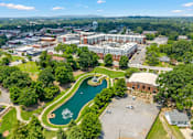 Thumbnail 47 of 47 - A large building complex with a fountain in the middle of a green area.