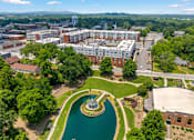 Thumbnail 46 of 47 - A large building complex with a fountain in the middle of a green area.