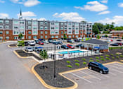 Thumbnail 45 of 47 - A parking lot with a pool and a building in the background.