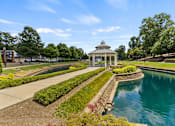 Thumbnail 36 of 47 - A gazebo is situated in the middle of a garden with a pond.