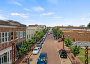 Thumbnail 32 of 47 - A street view of a town with cars parked on the side of the road.