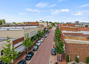 Thumbnail 31 of 47 - A street view of a town with cars parked on the side of the road.