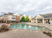 Thumbnail 7 of 78 - A swimming pool in front of a building with a patio and chairs.