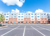 Thumbnail 1 of 47 - A large building with a parking lot in front of it.