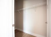 Thumbnail 19 of 47 - A white closet with a door and a shelf.