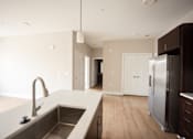 Thumbnail 13 of 47 - A modern kitchen with a stainless steel refrigerator and a sink with a faucet.