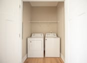 Thumbnail 9 of 47 - Two white washing machines in a small laundry room.