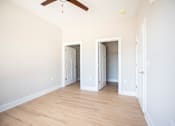 Thumbnail 11 of 47 - A room with a ceiling fan and three open doors.