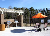 Thumbnail 5 of 37 - A patio with a grill and chairs under a white pergola.