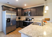 Thumbnail 29 of 37 - A kitchen with a granite counter top and stainless steel appliances.