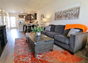 Thumbnail 31 of 37 - A living room with a grey couch and a wooden coffee table.