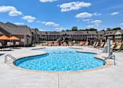 Thumbnail 4 of 37 - A large outdoor swimming pool surrounded by lounge chairs and umbrellas.