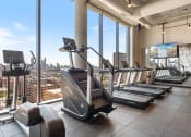 Thumbnail 18 of 35 - a gym with cardio machines and a view of the city