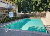 Thumbnail 4 of 8 - a swimming pool in front of a building with a fence