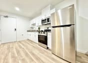 Thumbnail 14 of 19 - A modern kitchen with a stainless steel refrigerator and wooden flooring.