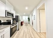 Thumbnail 12 of 19 - A modern kitchen with white cabinets and stainless steel appliances.
