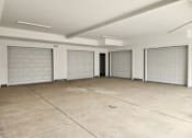 Thumbnail 11 of 14 - A spacious garage with four doors and a concrete floor.