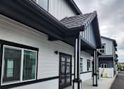 Thumbnail 12 of 14 - A white building with black trim and a black awning.