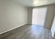 Thumbnail 8 of 10 - A room with wooden flooring and a window with blinds.