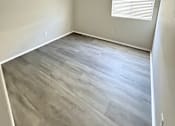 Thumbnail 10 of 10 - A room with a window and wooden flooring.