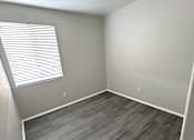 Thumbnail 9 of 10 - A room with a wooden floor and a window with blinds.