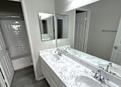 Thumbnail 5 of 10 - A bathroom with a marble countertop and a large mirror.