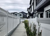 Thumbnail 14 of 14 - A white fence runs down the side of a sidewalk.
