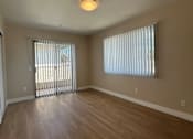 Thumbnail 5 of 13 - A room with wooden floors and a window with blinds.