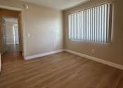 Thumbnail 3 of 13 - A room with wooden flooring and a window with blinds.
