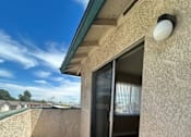 Thumbnail 7 of 13 - A balcony with a sliding glass door and a wall lamp.