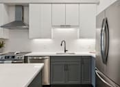 Thumbnail 9 of 21 - A modern kitchen with a stainless steel refrigerator and a white countertop.