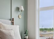 Thumbnail 2 of 21 - A bedroom with a bed, pillows, a lamp, and a window overlooking a parking lot.