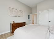 Thumbnail 5 of 21 - A bedroom with a bed, dresser, and two framed pictures on the wall.