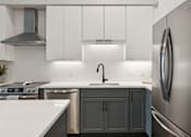 Thumbnail 7 of 21 - A modern kitchen with a stainless steel refrigerator and a white countertop.