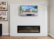 Thumbnail 15 of 21 - A modern living room with a fireplace and a TV mounted above it.