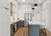 Thumbnail 12 of 21 - A modern kitchen with a white countertop and stainless steel appliances.