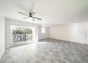 Thumbnail 12 of 61 - A room with a ceiling fan and a sliding glass door leading to a balcony at Red Bay Apartment Complex, Jacksonville, FL, 32211