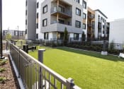 Thumbnail 11 of 28 - picture of an apartment complex with a grassy area and a fence