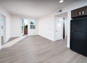 Thumbnail 6 of 12 - a living room with white walls and a black refrigerator