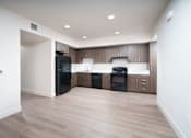 Thumbnail 5 of 12 - an empty kitchen with wood flooring and a black refrigerator
