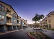 Thumbnail 1 of 22 - a development of townhouses and condominiums on a street with a tree in the middle