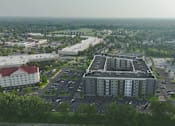 Thumbnail 4 of 4 - A large grey building with a parking lot in front of it.