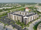 Thumbnail 3 of 4 - A large apartment complex with a parking lot in front.