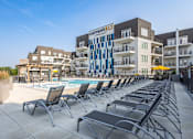 Thumbnail 22 of 60 - A pool area with chairs and a building with a sign that says "Current 812".