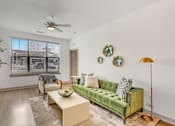 Thumbnail 2 of 34 - A living room with a green couch and a ceiling fan.