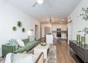 Thumbnail 5 of 34 - A living room with a green couch and a white ceiling fan.