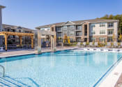 Thumbnail 22 of 27 - a swimming pool with an apartment building in the background at Arlington Farms, Greenwood, 46143