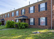 Thumbnail 19 of 30 - a brick apartment building with a green lawn in front of it