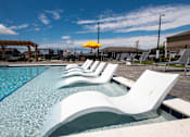 Thumbnail 20 of 48 - Pool area with white lounge chairs in water at Allure Apartments, Whiteland, 46184