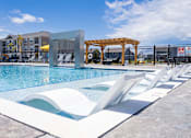 Thumbnail 41 of 48 - Swimming pool with tanning ledge and white loungers at Allure Apartments, Whiteland, IN 46184